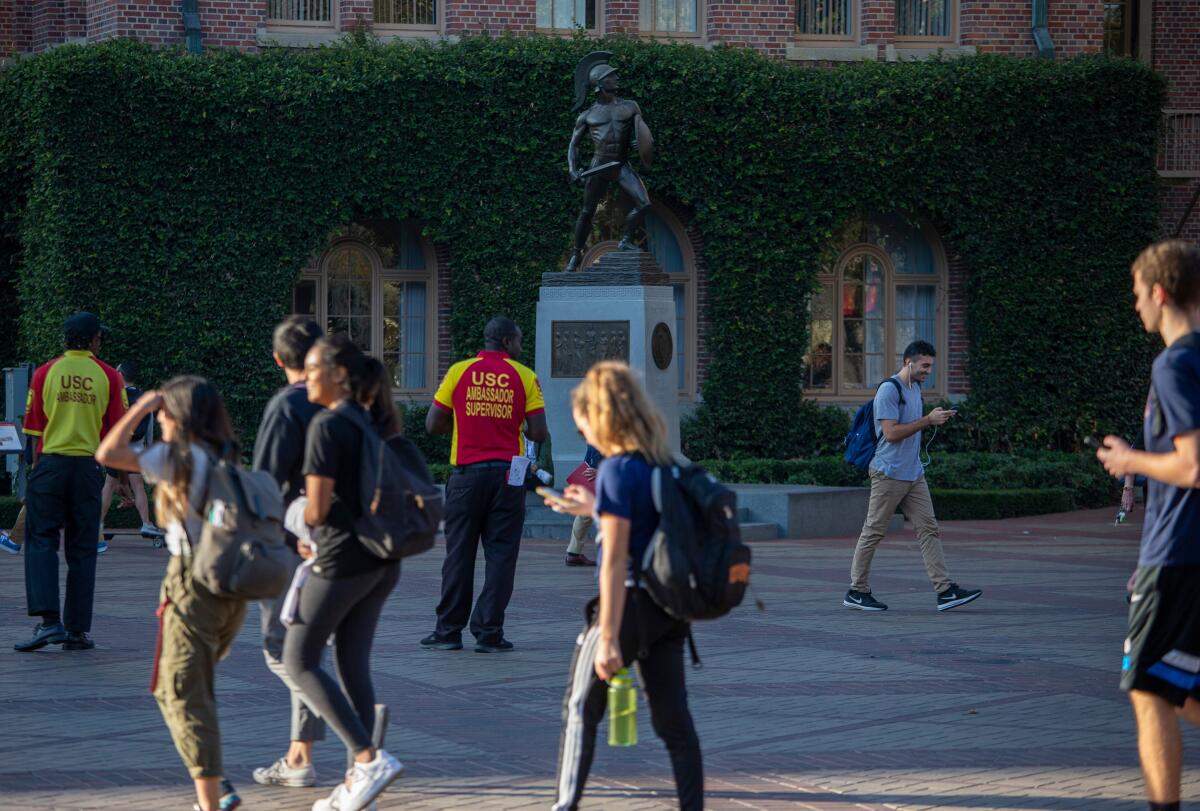 Several USC students walk by Tommy Trojan in November 2019. 
