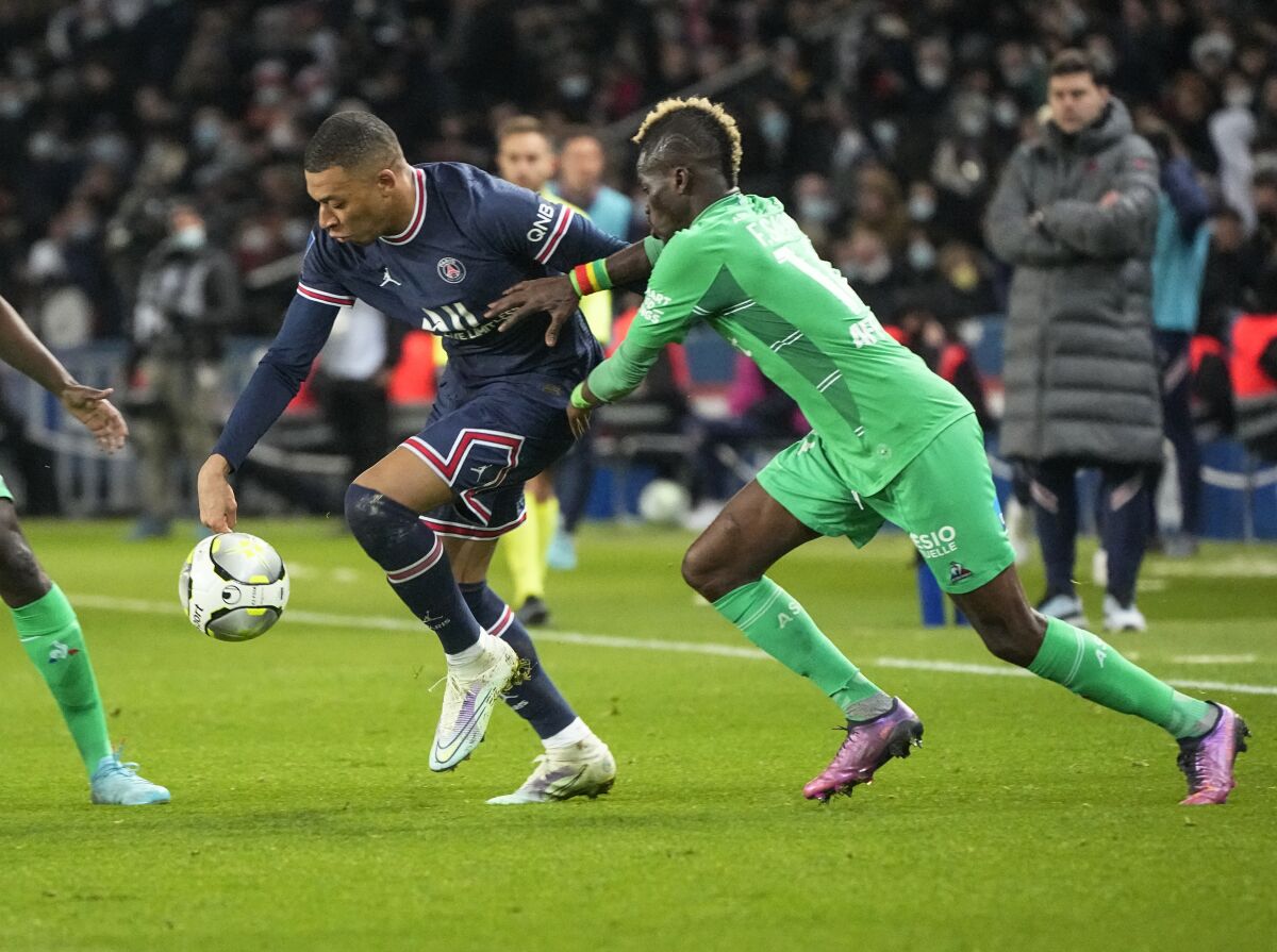 PSG's Kylian Mbappe, left, challenges for the ball with Saint-Etienne's Falaye Sacko during the French League One soccer match between Paris Saint Germain and Saint-Etienne at the Parc des Princes stadium in Paris, Saturday, Feb. 26, 2022. (AP Photo/Michel Euler)