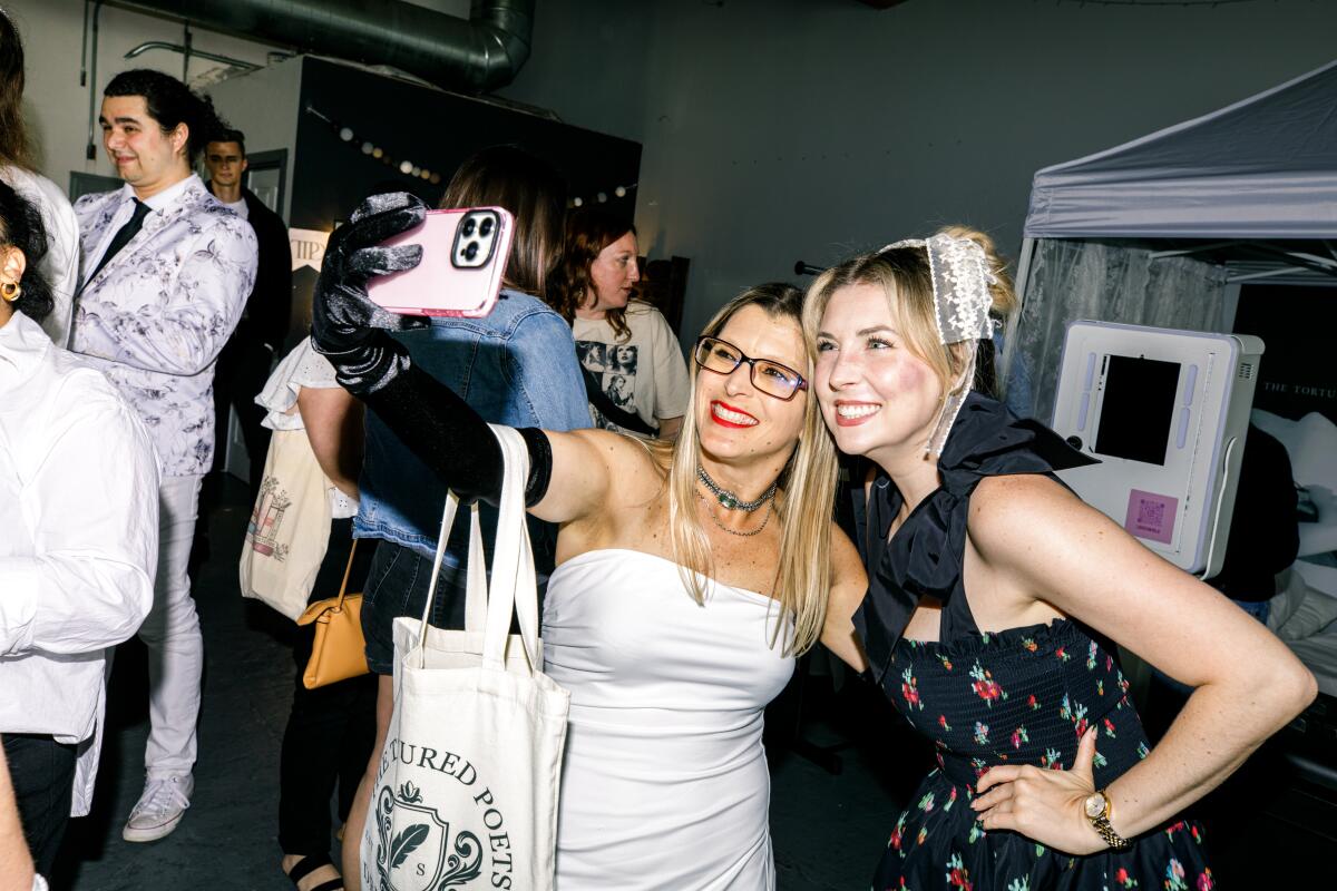 A photo of two women smiling and taking a selfie together at Taylor Swift's listening party.