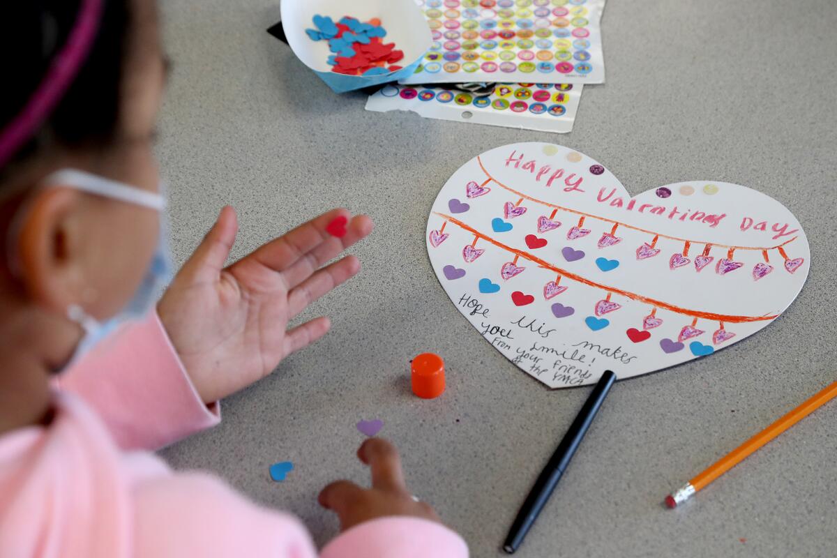 Third-grader Leila, 8, adds another red heart to her valentines card Wednesday at the Peterson Elementary School YMCA.