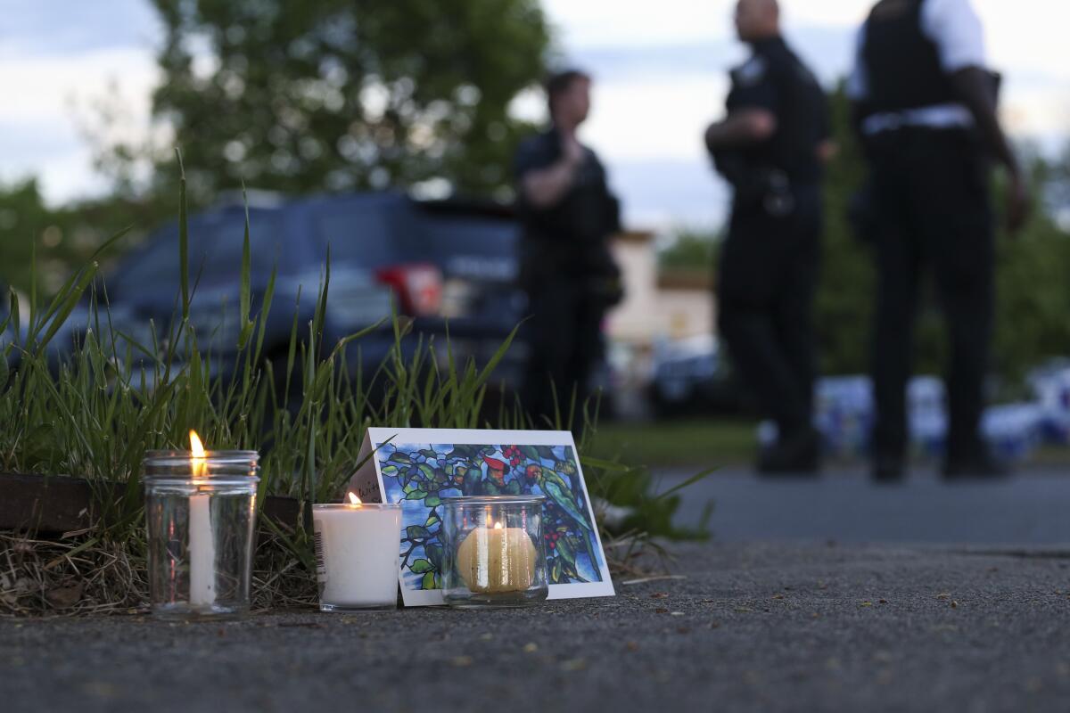 Candles and a card on the ground, with police in the background.