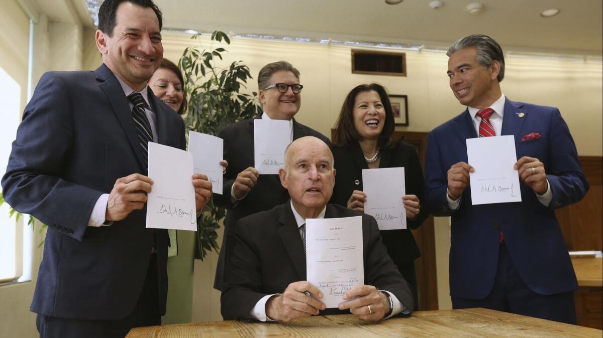 Gov. Jerry Brown and leaders from the state Legislature and Supreme Court hold up copies of the bail reform bill on Aug. 28.