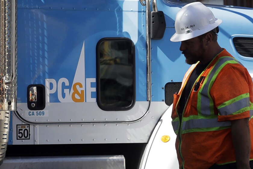 A Pacific Gas & Electric worker walks in front of a truck