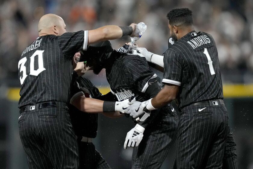 Chicago White Sox's Luis Robert Jr., center, is greeted by teammates after he drove in the winning run off Miami Marlins relief pitcher Dylan Floro during the ninth inning of a baseball game Friday, June 9, 2023, in Chicago. (AP Photo/Charles Rex Arbogast)