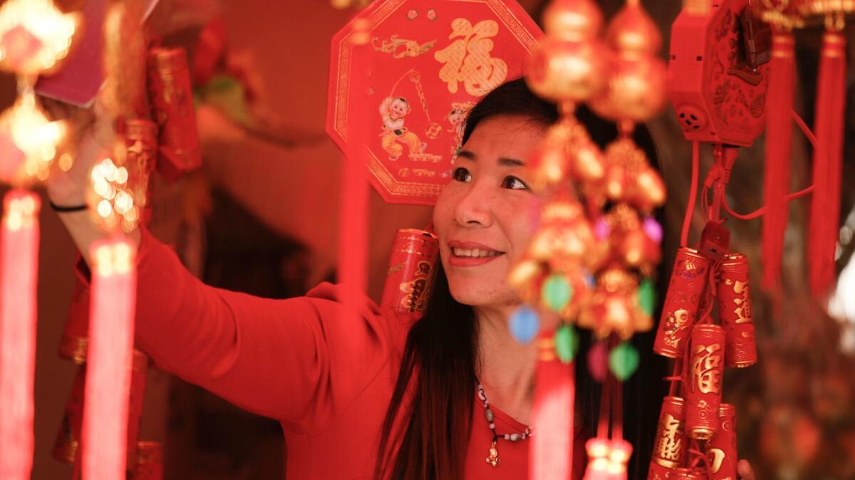 Lily Ting Ma of China takes a selfie in one of the souvenir booths selling Lunar New Year items in the Flower Festival.