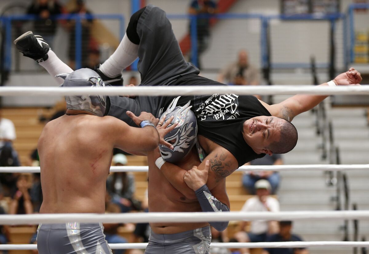 Lil Cholo, top, get thrown by Phoenix Star as partner Zokre, left, moves in during a lucha libre match at Expo Lucha at Harry West Gymnasium at San Diego City College on August 18, 2019. The three-day event featured live wrestling, along with meet and greets and vendor booth.