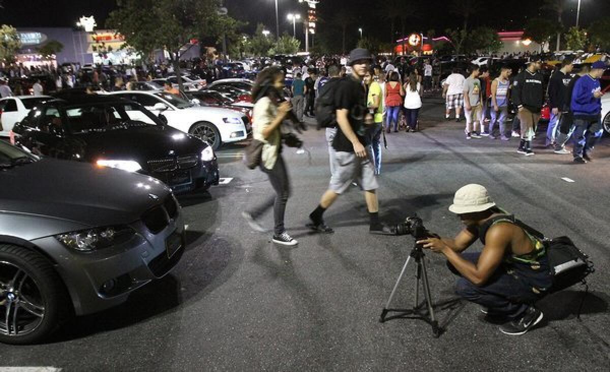 A photographer takes a picture of one of thousands of cars at the Empire Center in Burbank is the focus point for a multi-hundred, maybe thousand car youth gathering for thousands on Tuesday, August 13, 2013. The Burbank Police Department, in a mutual aid effort, closed streets leading to the mall as early as 6:30 turning away thousands.