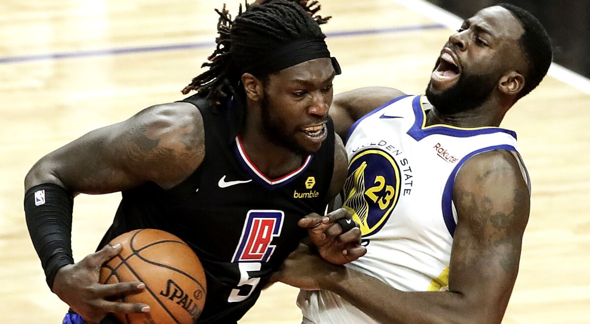 Clippers center Montrezl Harrell tries to power his way past Warriors forward Draymond Green during a game last season.