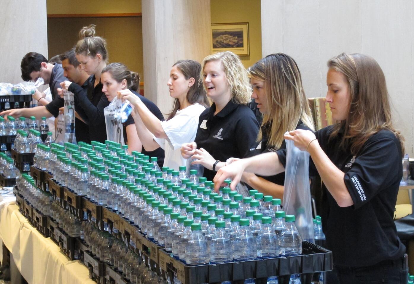 Workers and volunteers at the University of South Carolina bag bottled water for distribution to students on campus in Columbia, S.C., where flooding has made tap water unsuitable to drink without boiling.