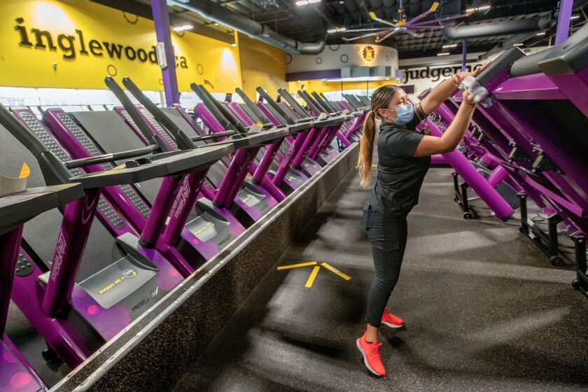 An employee disinfects machines at Planet Fitness on Imperial Highway in Inglewood last year.