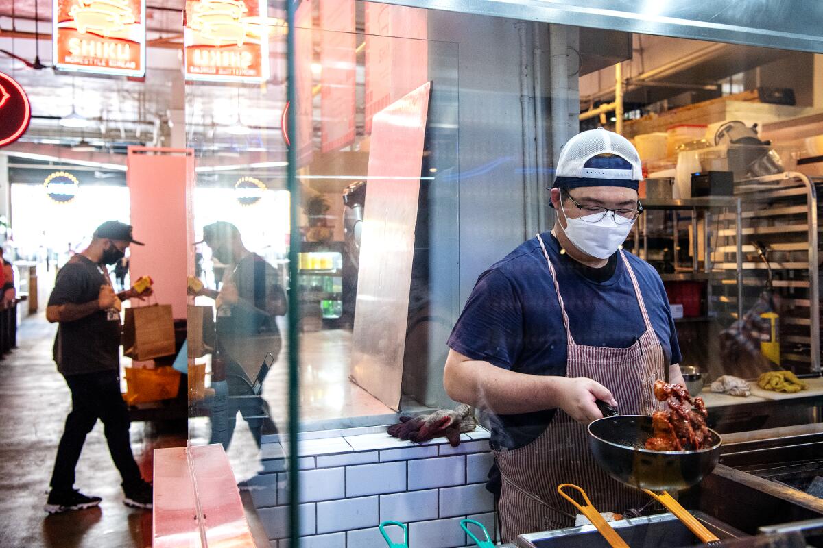 A man holding pan with food prepares and order in a kitchen