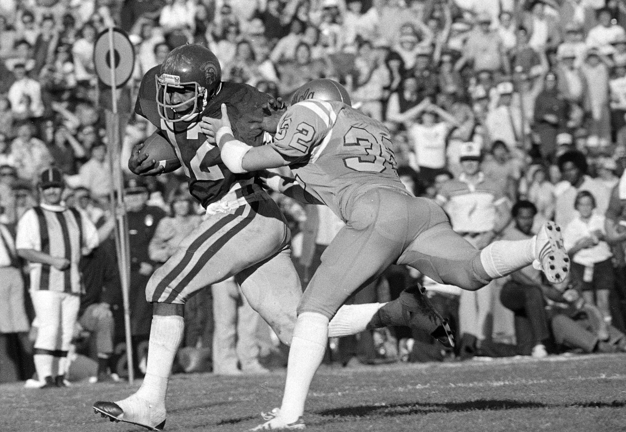 USC'den Charles White, 26 yarda touchdown koşusu için UCLA'dan Tom Sullivan tarafından koşuyor.