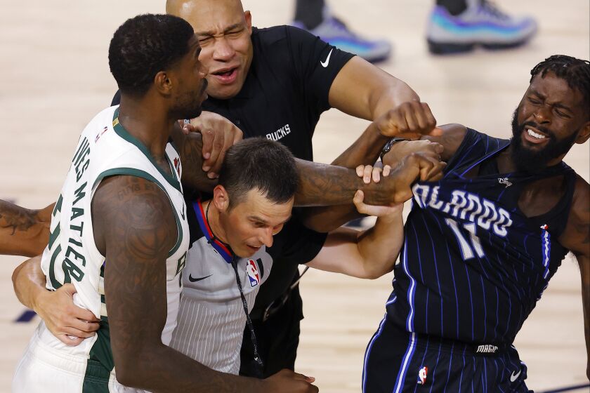 Milwaukee Bucks' Marvin Williams (20) grabs the jersey of Orlando Magic's James Ennis III (11) as referee Kevin Scott and Bucks assistant coach Darvin Ham tries to break it up during Game 3 of an NBA basketball first-round playoff series, Saturday, Aug. 22, 2020, in Lake Buena Vista, Fla. (Mike Ehrmann/Pool Photo via AP)
