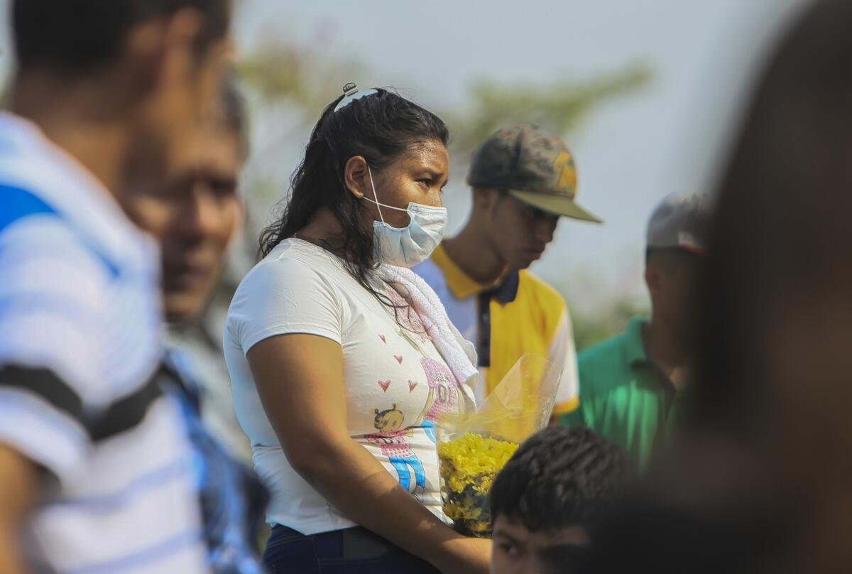 A woman in a surgical mask attends a funeral May 11 at a cemetery in Managua, Nicaragua.