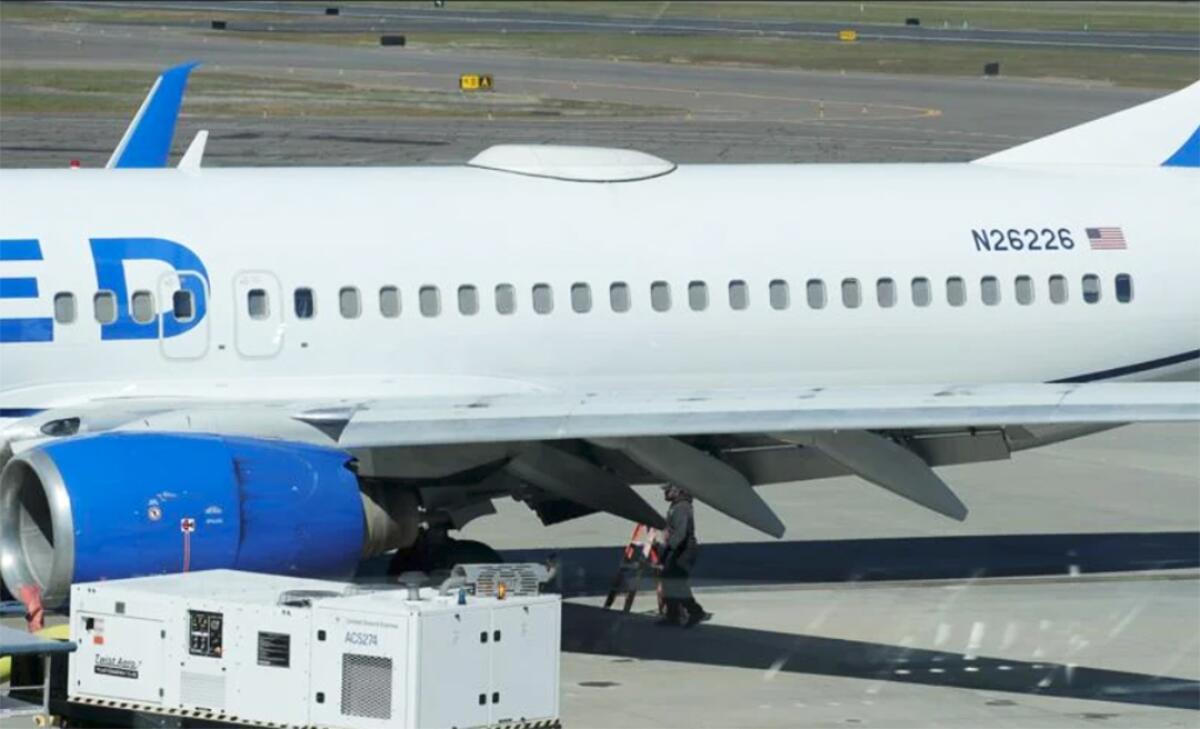 Medford Jet Center staff investigate beneath a United Boeing 737-800 that landed at the Medford airport with a missing panel.