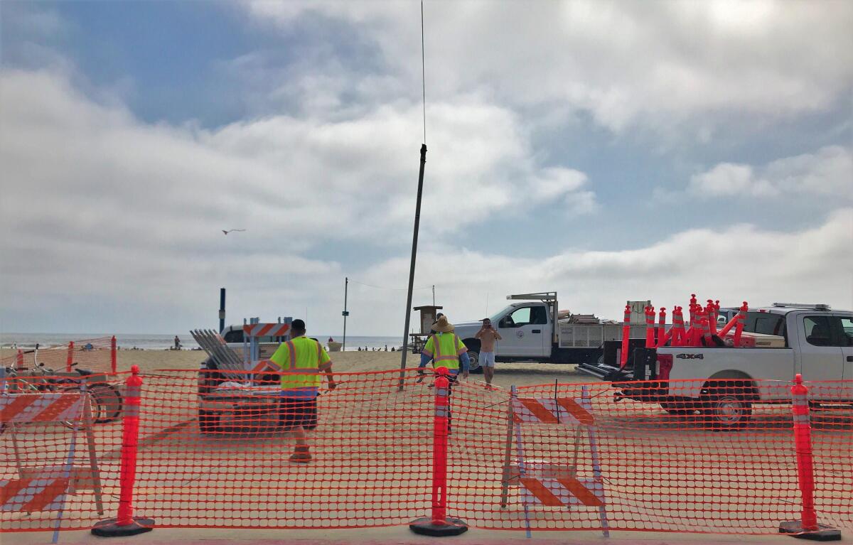 Newport Beach public works employees set up fencing near the 28th Street beach in Newport Beach on Thursday.