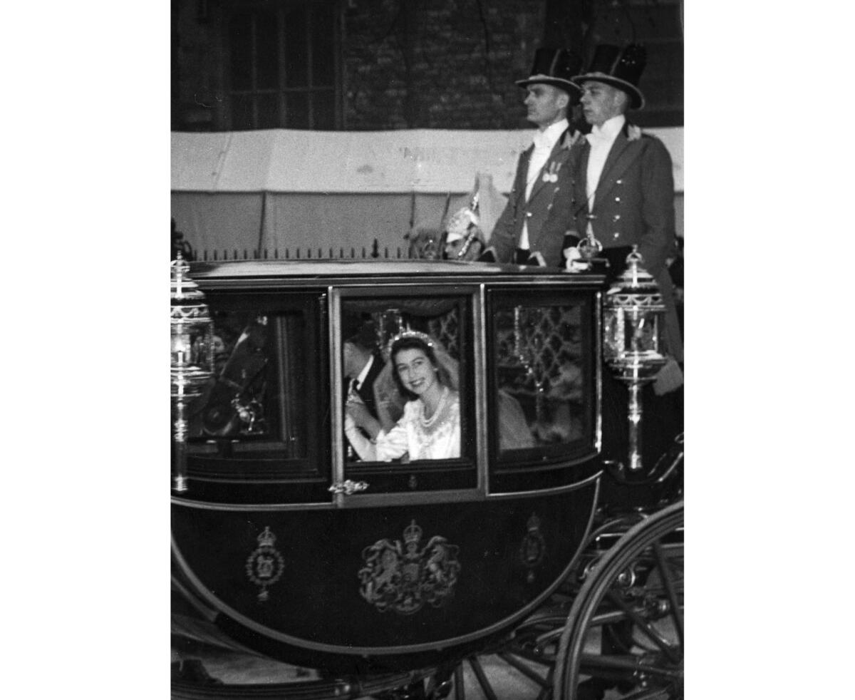 Inside the horse-drawn Glass Coach, Philip holds Elizabeth's hand.