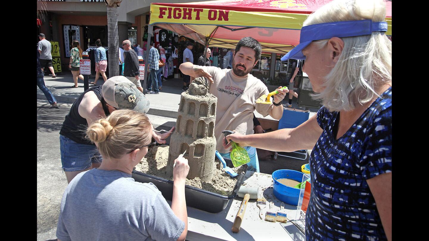 Architecture team Kate Curtain, Kelly Johnson, Justin Curtain, and Susan Cizek, from left, contruct a mini "Leaning Tower of Pisa" during the Dig it! Sandcastle Construction Instruction event on Main Street in downtown Huntington Beach on Saturday.