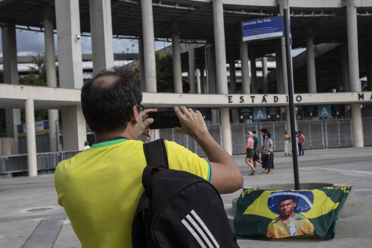 Un hombre fotografía un letrero con el nuevo nombre de la avenida que rodea el Estadio 