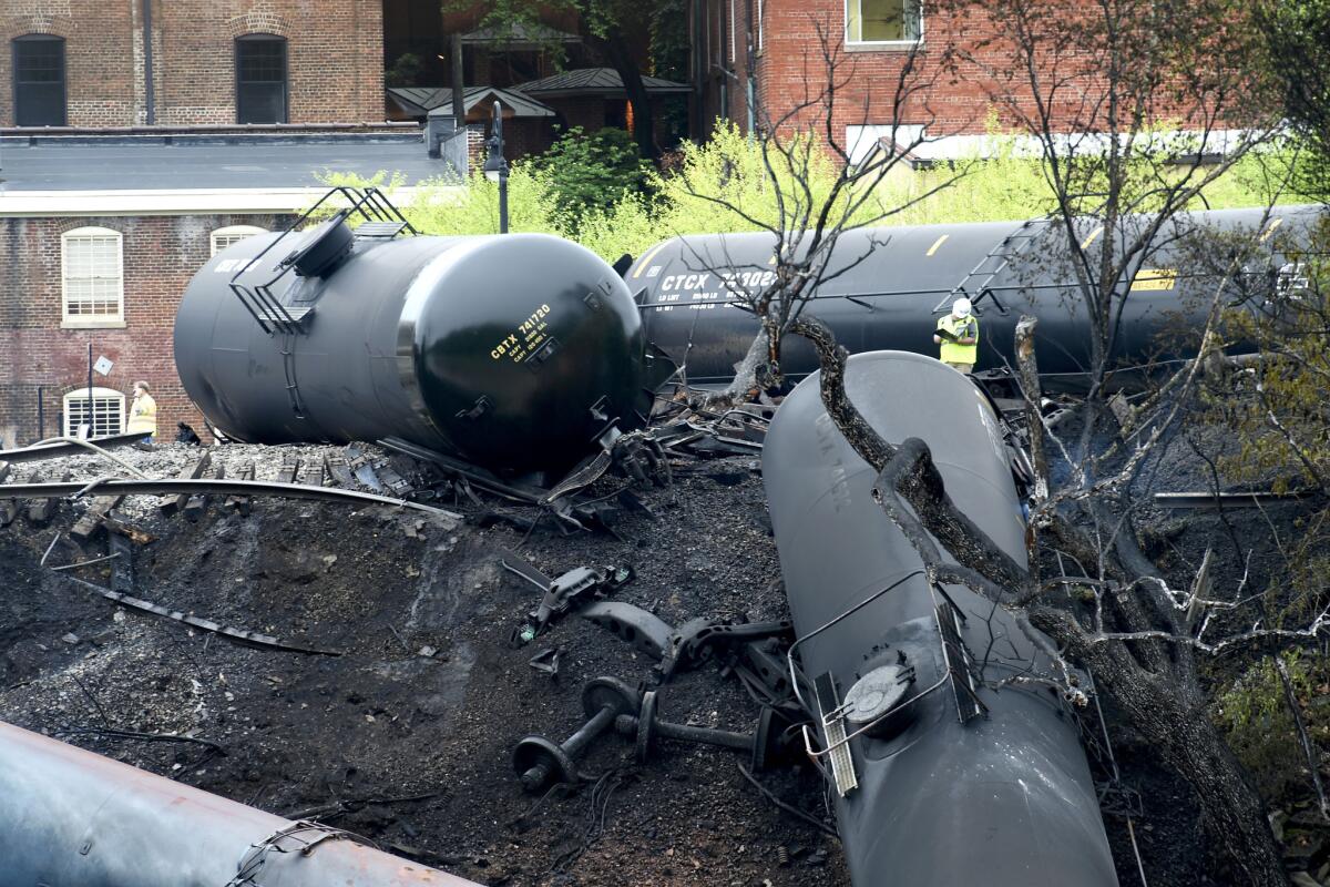 A worker stands by damaged tanker cars where several CSX tanker cars carrying crude oil derailed and caught fire along the James River near downtown Lynchburg, Va., on Thursday.