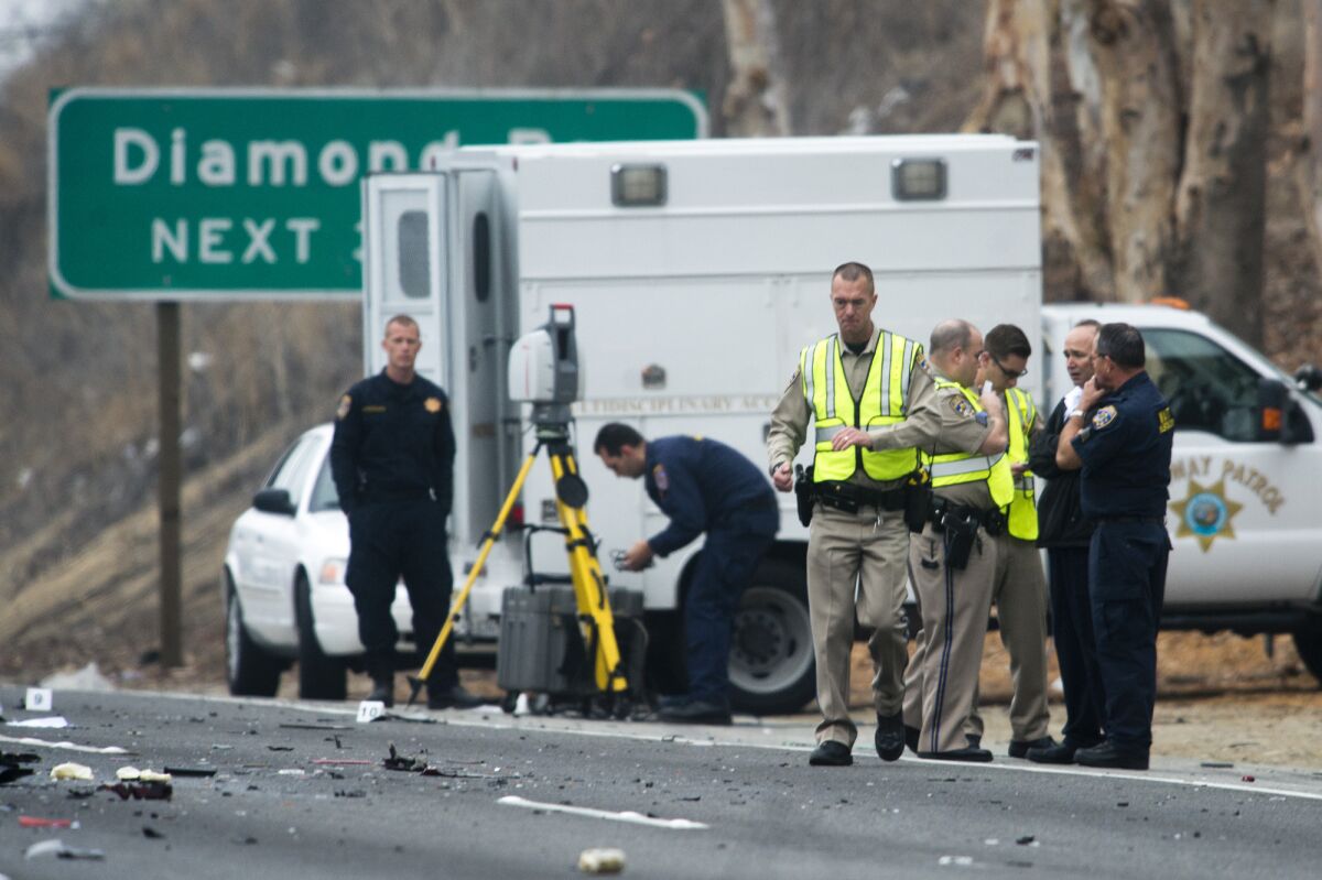 Officials investigate the scene of a three-vehicle crash where six people were killed on the westbound 60 Freeway in Diamond Bar.