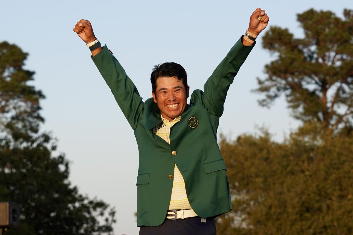 Hideki Matsuyama throws his arms in the air and grins while wearing the winner's green jack at the Masters 
