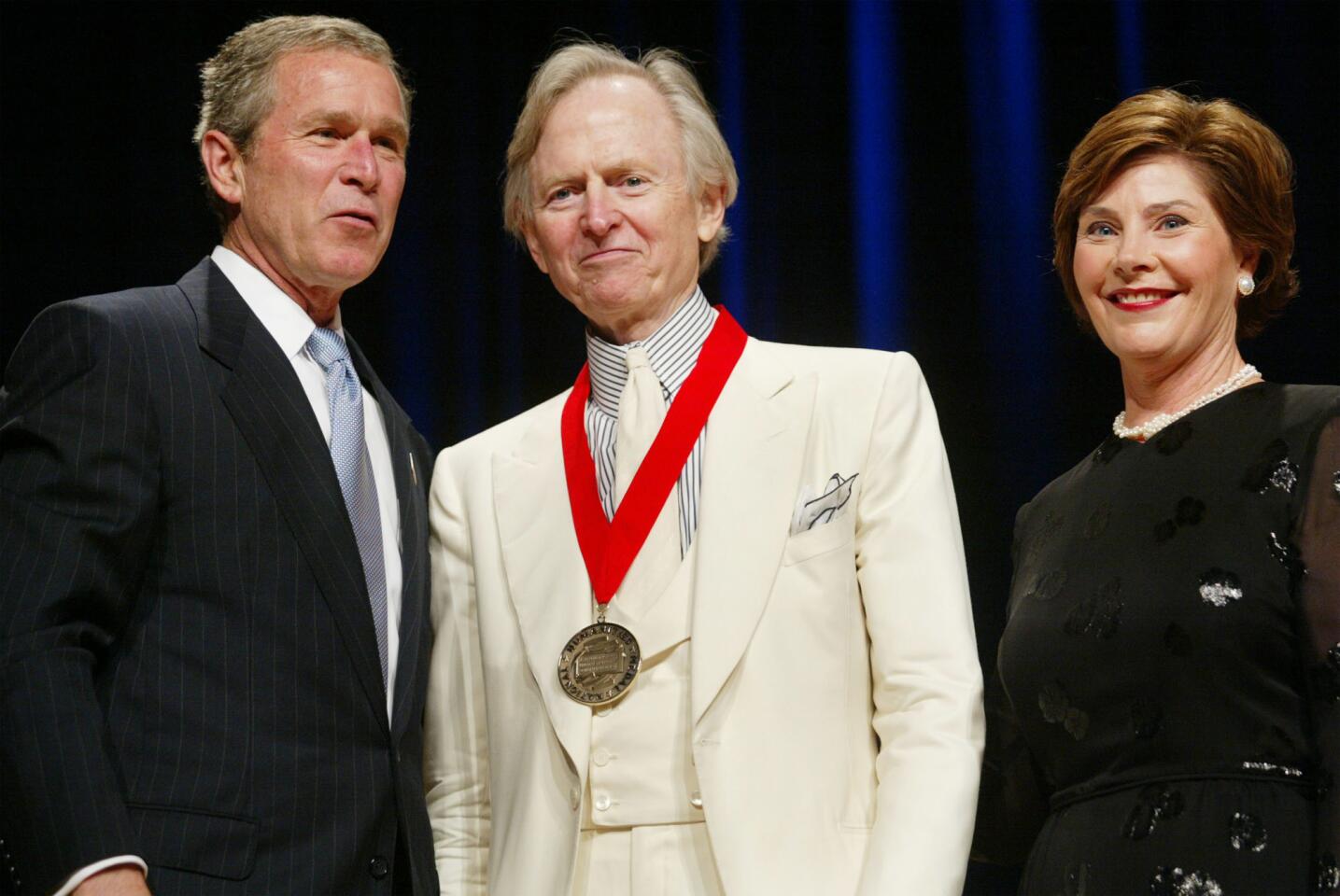 Wolfe is flanked by President George W. Bush and First Lady Laura Bush in 2002 during the National Endowment for the Arts National Medal Awards ceremony at Constitution Hall in Washington. Wolfe was a recipient of the National Humanities Medal.