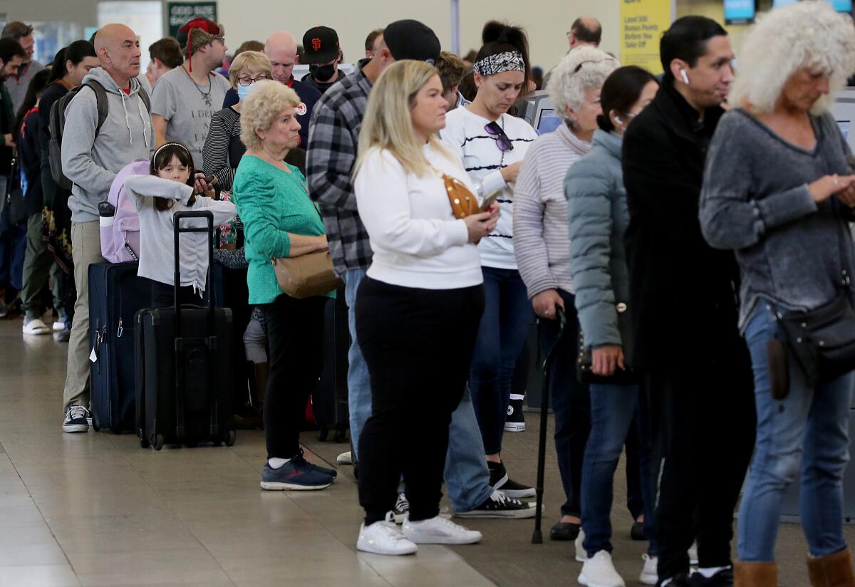 As Southwest Airlines continued to cancel flights, travelers wait in line at John Wayne Airport in Santa Ana. 