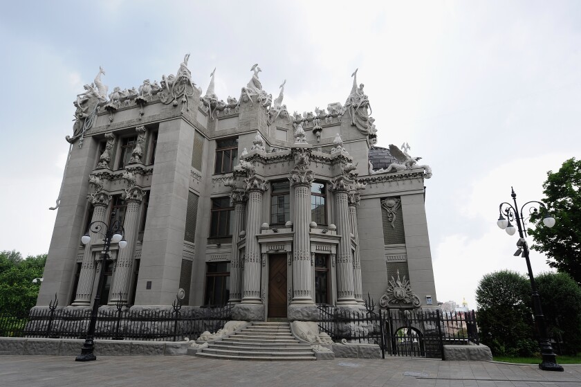 The facade of a large city building shows a roof line topped by a wild assemblage of sculptures.