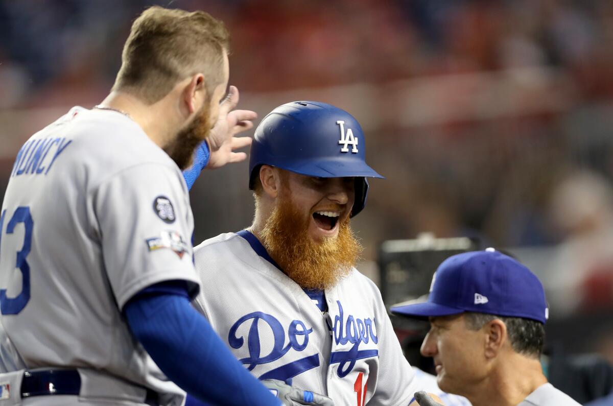 Dodgers third baseman Justin Turner celebrates with teammate Max Muncy, left, after hitting a first-inning home run against the Washington Nationals on Monday.
