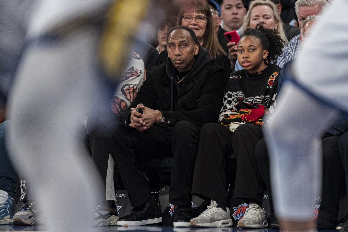 A man sits courtside at an NBA game.