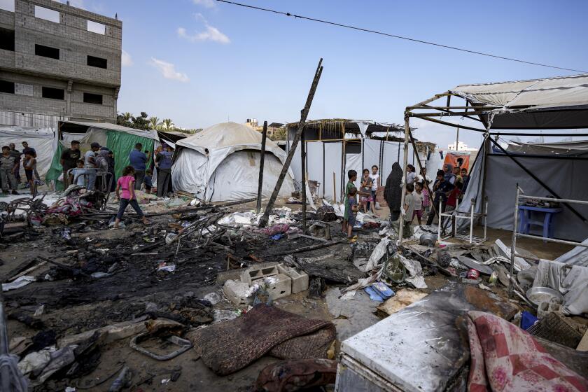 Palestinos inspeccionan los daños causados por un bombardeo israelí contra un campamento ubicado en el patio del Hospital Mártires de Al Aqsa, en Deir al-Balah, el domingo 4 de agosto de 2024. (AP Foto/Abdel Kareem Hana)