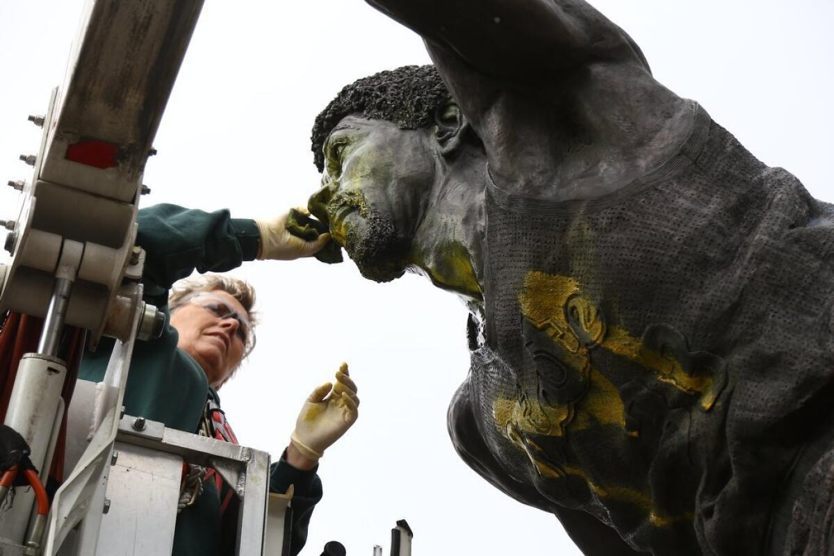 Tracy Harris cleans a statue of Magic Johnson on the campus of Michigan State University on Thursday.