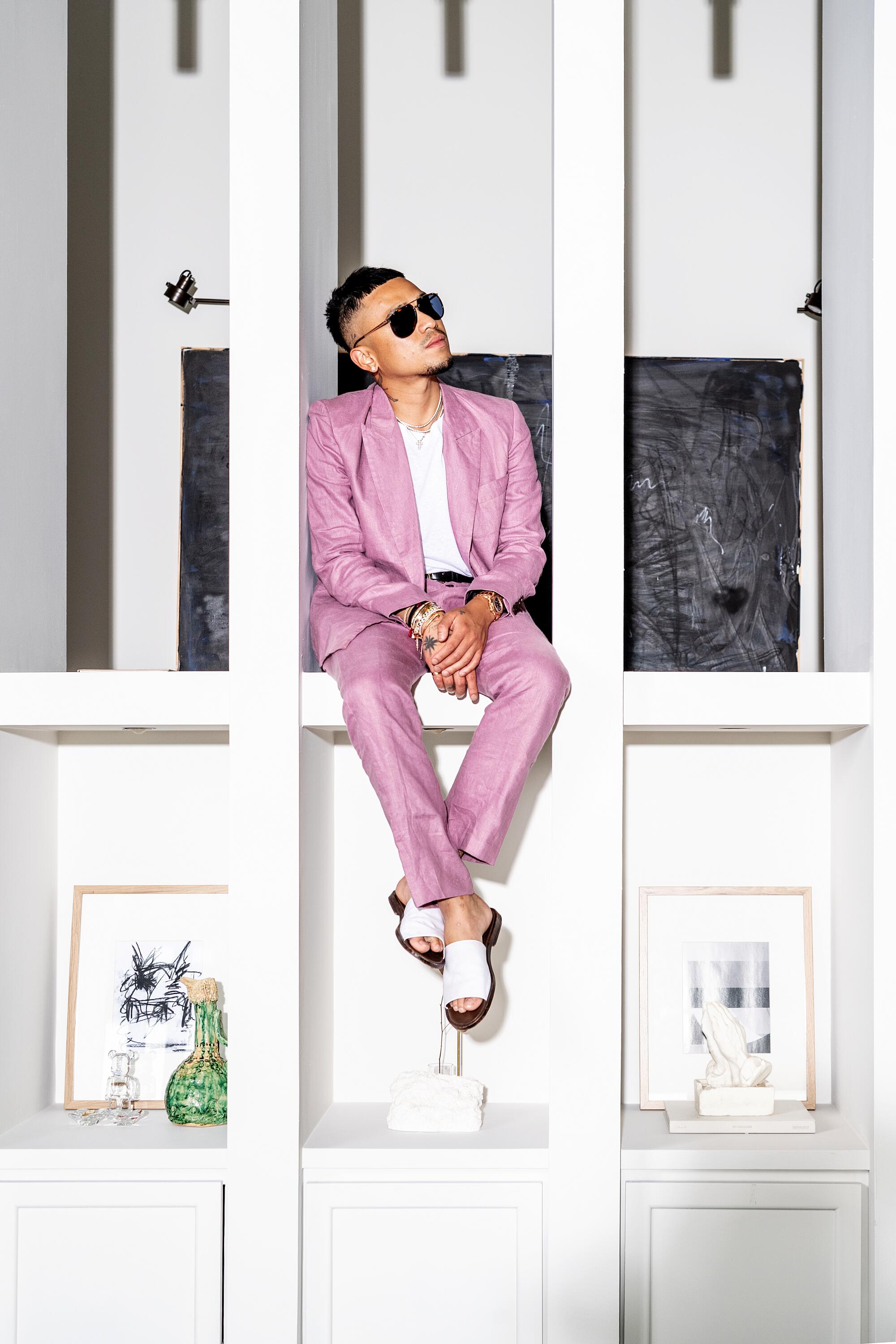 A photo of a man in mauve suit in a windowsill.