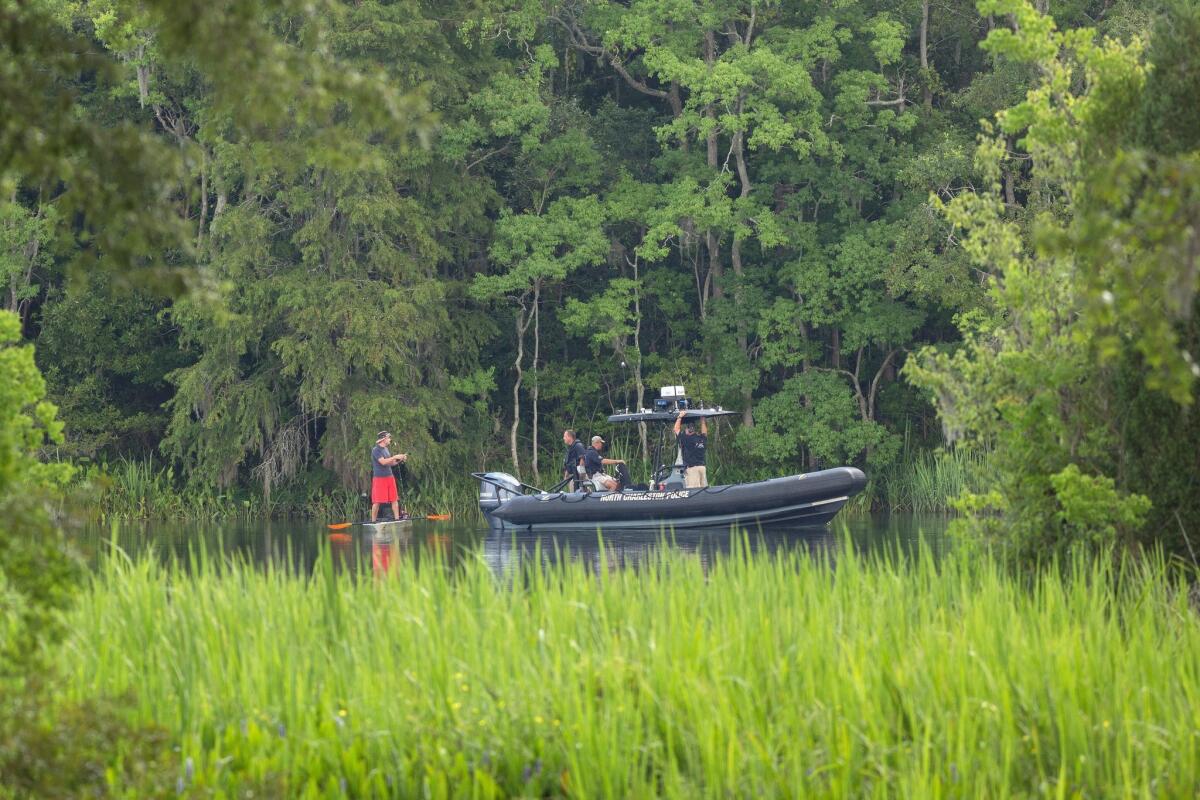 North Charleston police assist in a water search in a residential area where a U.S. Air Force F-16 fighter aircraft collided with a small private airplane near Moncks Corner, S.C., on Tuesday.
