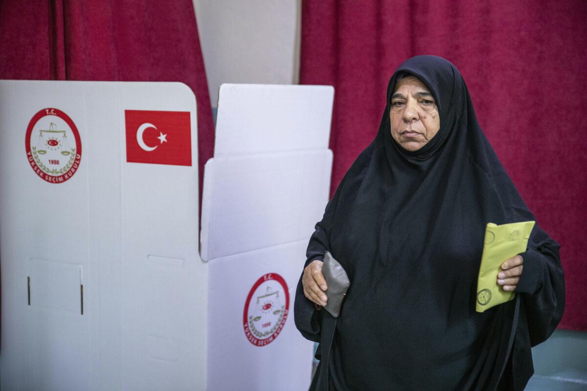 A woman in a dark head covering holds a ballot.