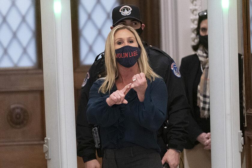 Rep. Marjorie Taylor Greene responds to journalists as she passes through a newly installed metal detector outside the House Chamber.