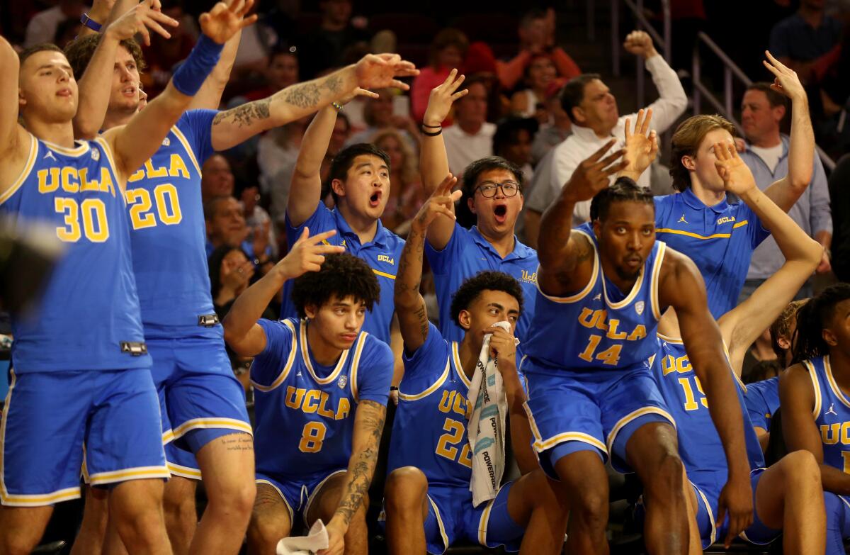 UCLA players on the bench celebrate Lazar Stefanovic hitting a 3-pointer against USC
