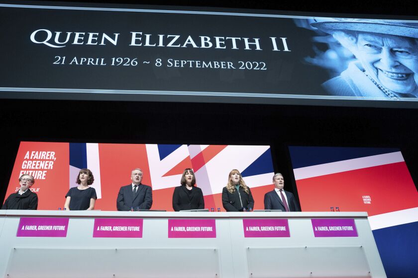 Labour party leader Keir Starmer, right, leads tributes to Queen Elizabeth II as the national anthem is sung during the Labour Party Conference in Liverpool, Sunday Sept. 25, 2022. Britain’s opposition Labour Party opened its annual conference Sunday, with leaders attacking the “immoral” tax-cutting of the new Conservative government. (Stefan Rousseau/PA via AP)
