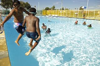 LOS ANGELES, CA - JULY 2, 2021 - - Mack Richardson, 9, left, and his cousin Damar Caine, 7, jump into the newly reopened Algin Sutton Pool in South Los Angeles on July 2, 2021. The Algin Sutton Pool is one of scores of public, commercial and residential aquatic facilities that were cleared to open across L.A. County after June 15. But experts warn that greater water access could lead to increased danger for kids this summer, since few have had access to swim lessons and previously strong swimmers may have lost or outgrown old skills. Meanwhile, many public pools have had to close due to lack of lifeguards and chlorine. (Genaro Molina / Los Angeles Times)