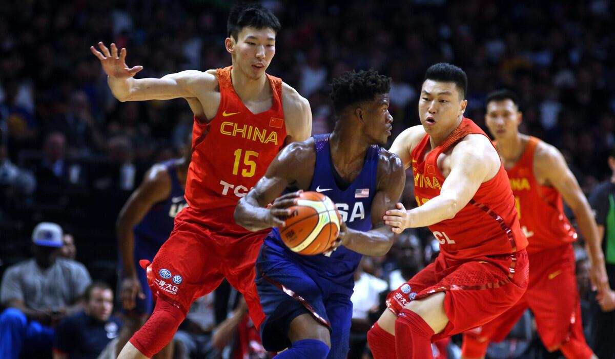 Jimmy Butler of the U.S. is guarded by Zhou Qi, left, and Li Gen of China in the first half of an exhibition game at Staples Center.