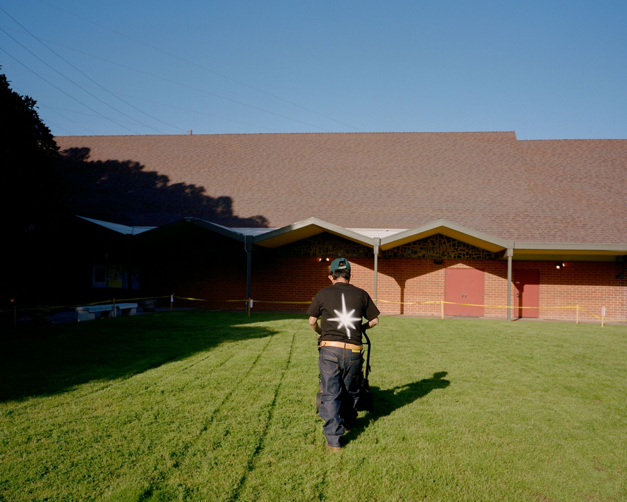 A landscaper cuts grass at a church.