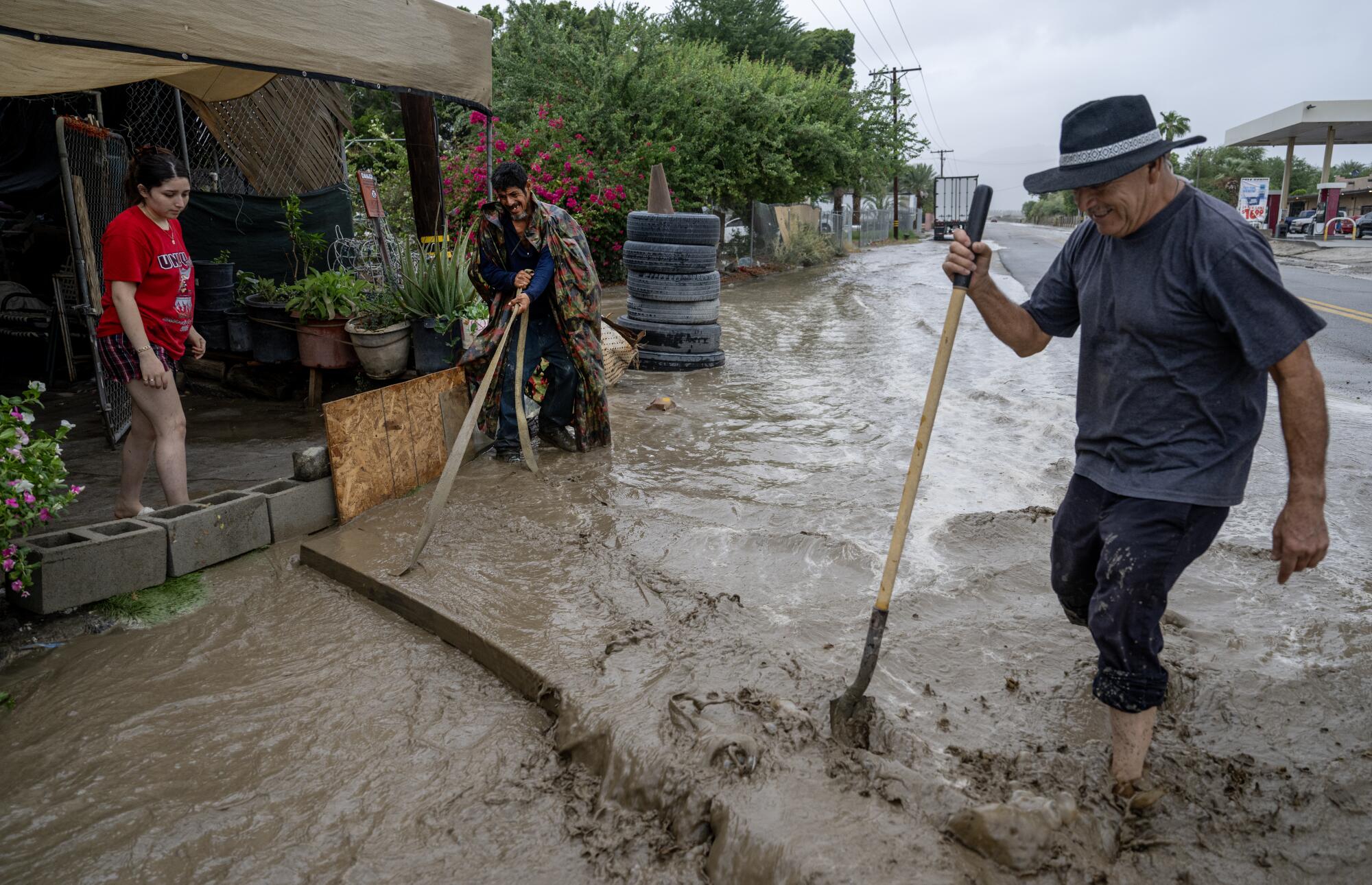 Two men hold a long-handled tools while standing in swirling muddy waters 