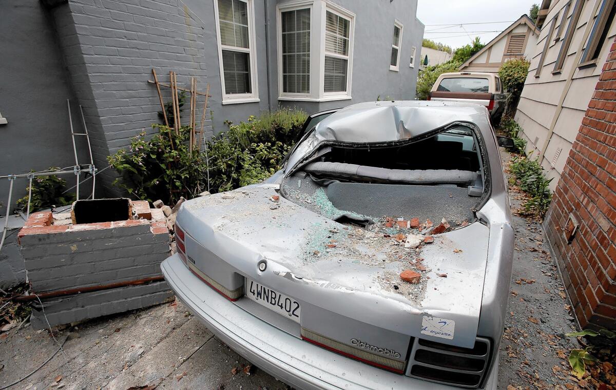 The remnants of a chimney rest beside a damaged car in the driveway of a red-tagged home in Vallejo on Monday. A 6.0-magnitude earthquake rocked the Bay Area on Sunday.