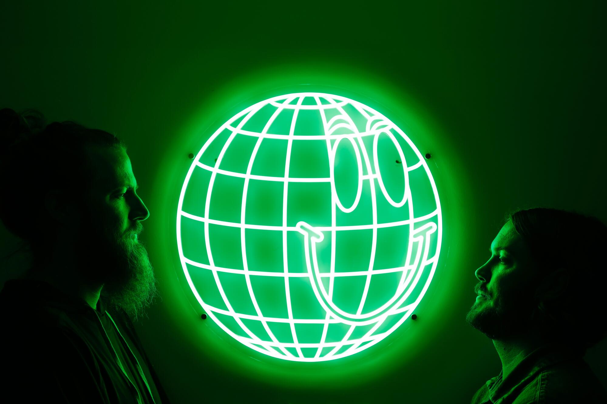 Two men face each other with a glowing neon green sign in between them