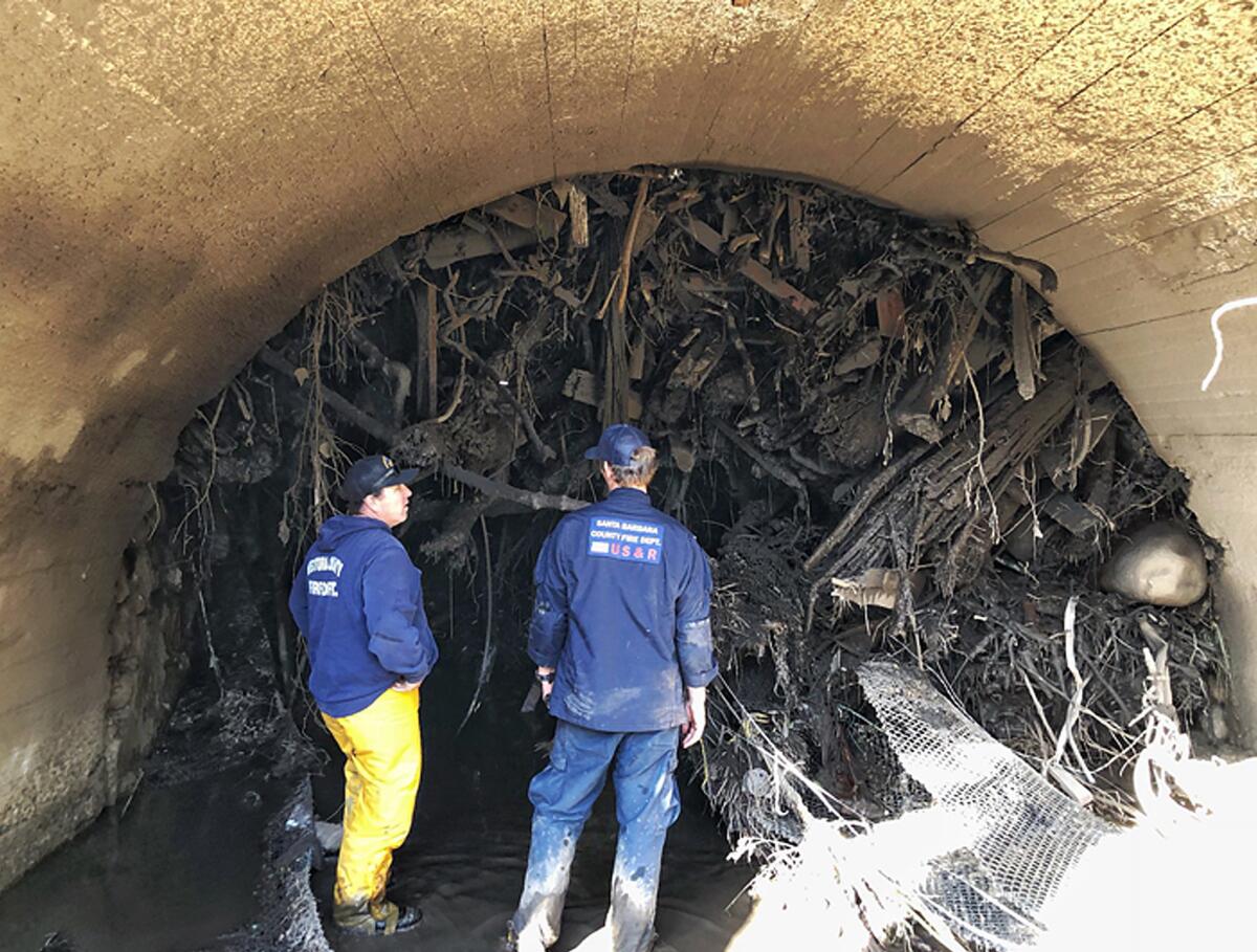 On Jan. 15, Santa Barbara County firefighters survey a wall of debris jammed under a bridge from the deadly rains and mudflow of Jan. 9 in Montecito.