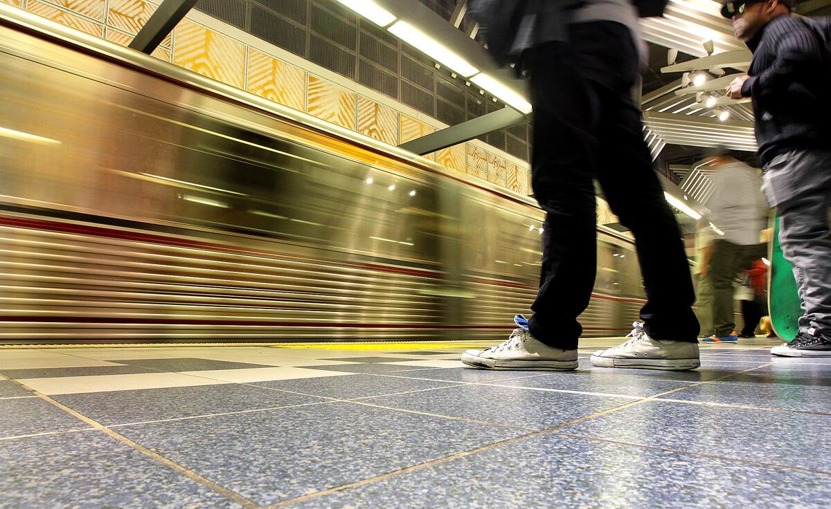 Riders stand back as a train arrives at the Universal City Red Line station.