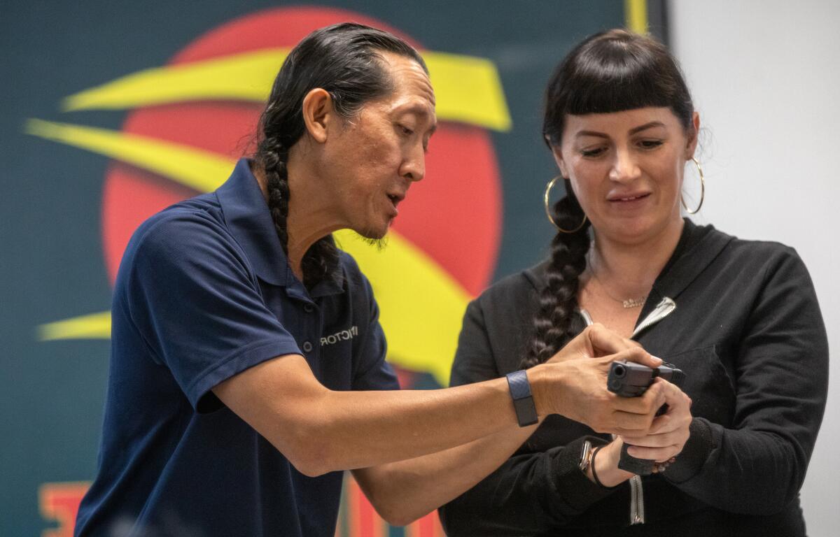 A man is instructing a woman during a firearms education course