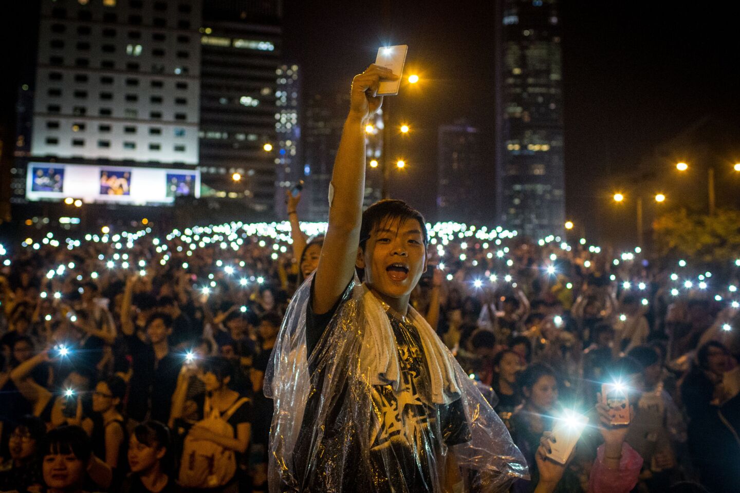 Protesters sing and wave their cellphones after a massive thunderstorm passed over outside the Hong Kong government complex on Sept. 30.