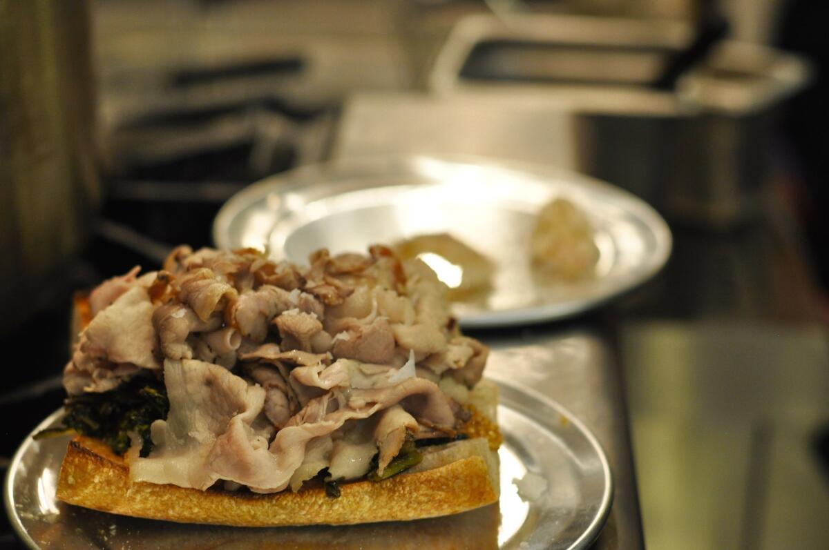 The porchetta dip sandwich at Knead & Co. at Grand Central Market includes thinly sliced porchetta, rapini, pork jus and pickled mustard seeds on baguette.